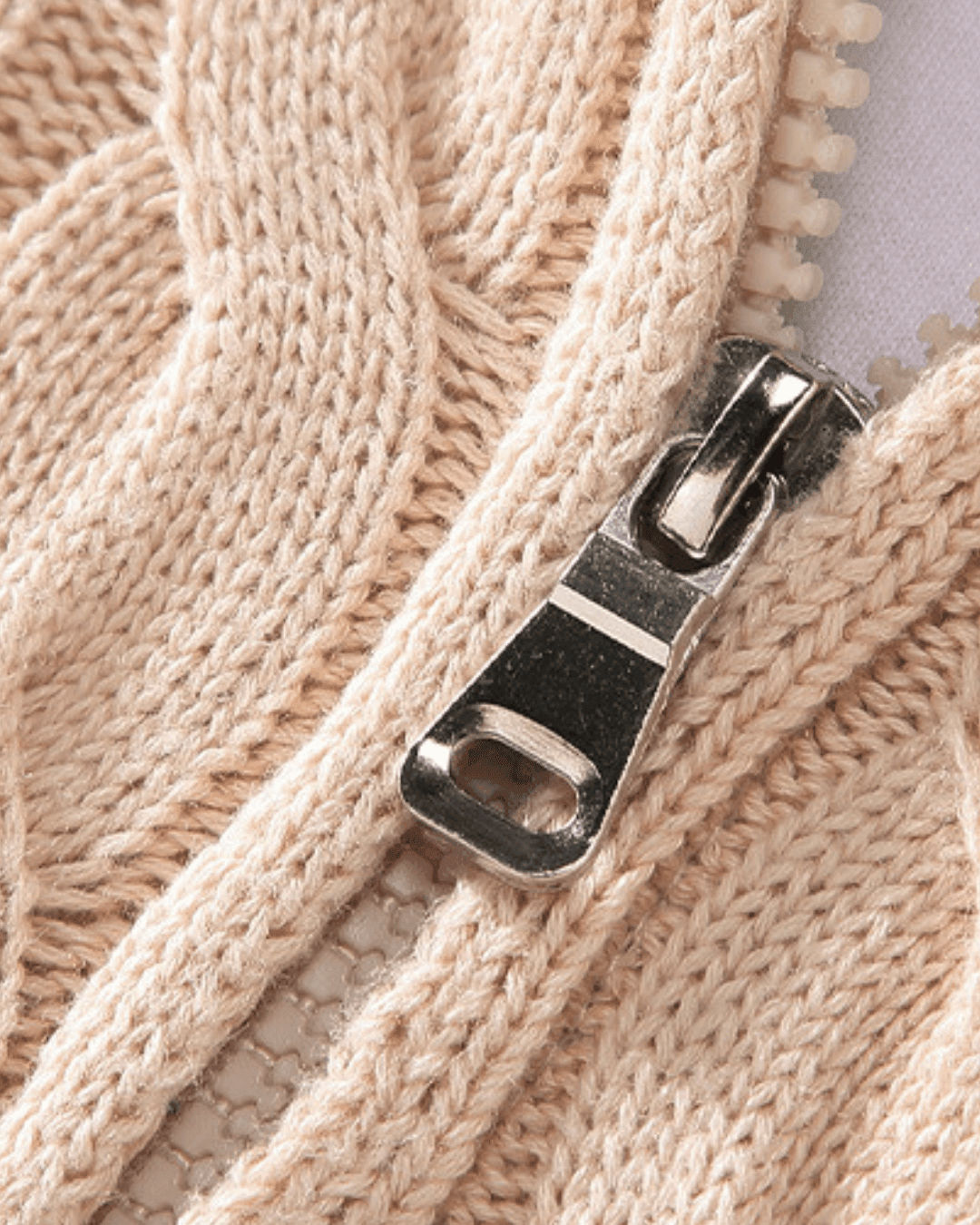 Close-up of a beige knit fabric with a metal zipper
