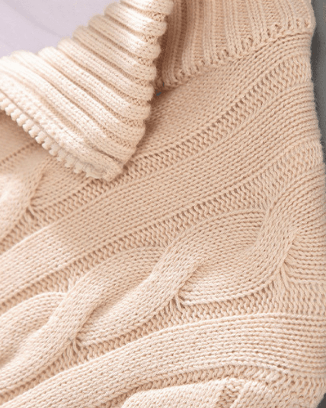 Close-up of a beige knitted sweater with cable pattern