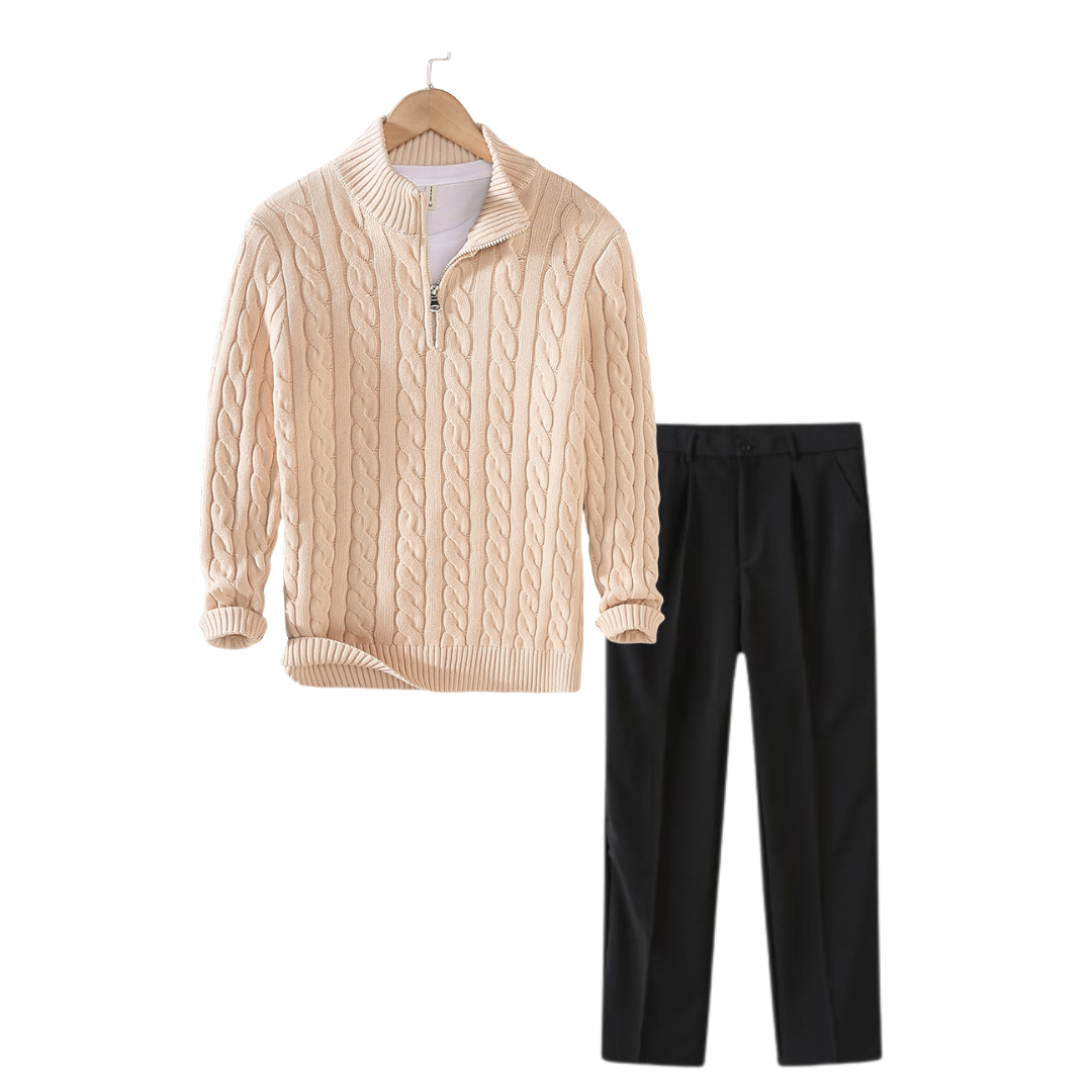 Beige cable knit sweater with a quarter zip and black pants on a white background