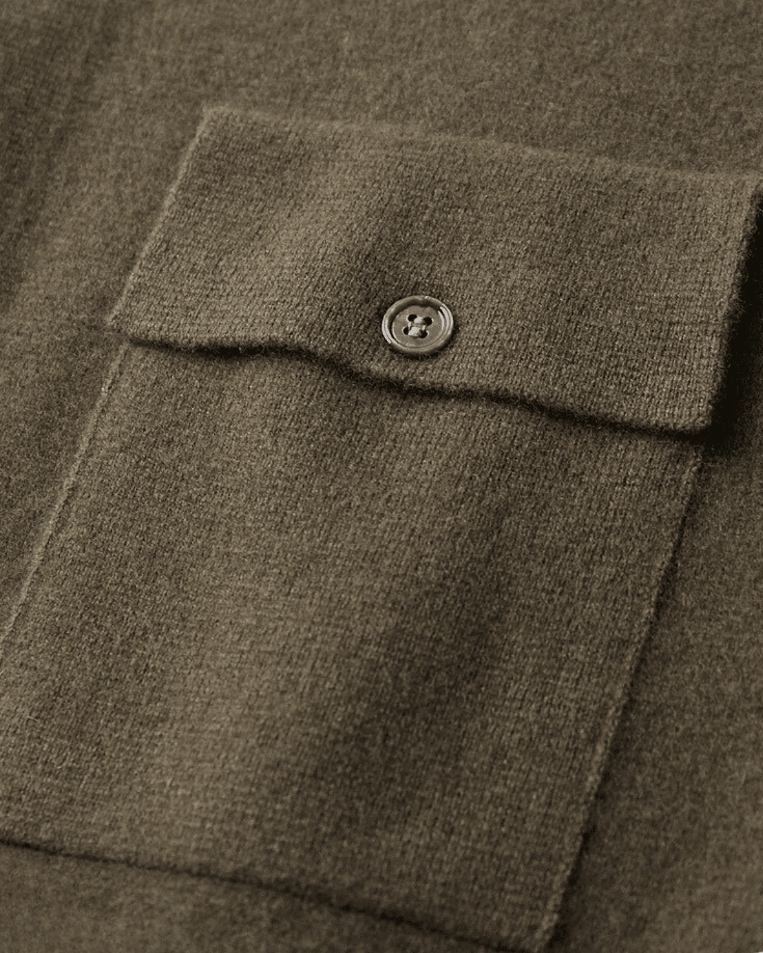 Close-up of a brown textured fabric with a button on a garment.