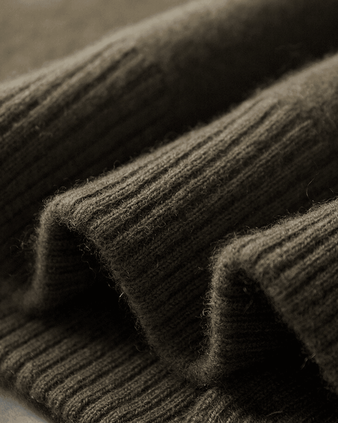 Close-up of folded dark gray sweaters with a textured fabric.